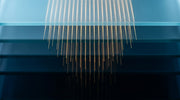 Abstract representation of Sylfirm X dual-wave RF microneedling, fine parallel light filaments descending through layered glass